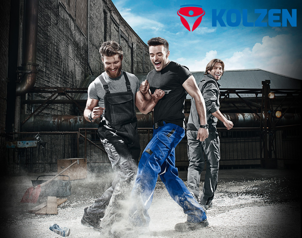 Drei Männer tragen KOLZEN Arbeitskleidung mit Latzhose und Arbeitshosen in Schwarz, Blau und Grau auf einer industriellen Baustelle
